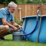 Homme inspectant la pompe et le filtre d'une piscine Intex hors-sol dans un jardin, vérifiant les connexions des tuyaux pour diagnostiquer une fuite ou un désamorçage